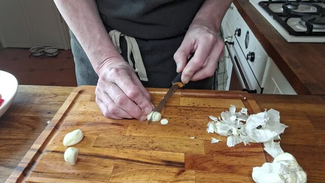 The cook slices the garlic. A man's hands are cutting garlic into slices. Concept of cooking, gastronomy and culinary. Footage from home kitchen