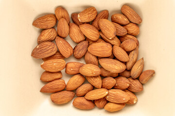 A small amount of roasted almonds in a ceramic dish, macro, top view.