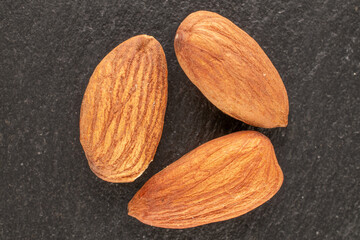 A few roasted almonds on slate stone, macro, top view.