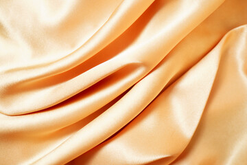 Close-up of yellow silk satin, draped fabric, gold color, elegant background. Beautiful wavy area for design, Close-up of blurred or blurred
