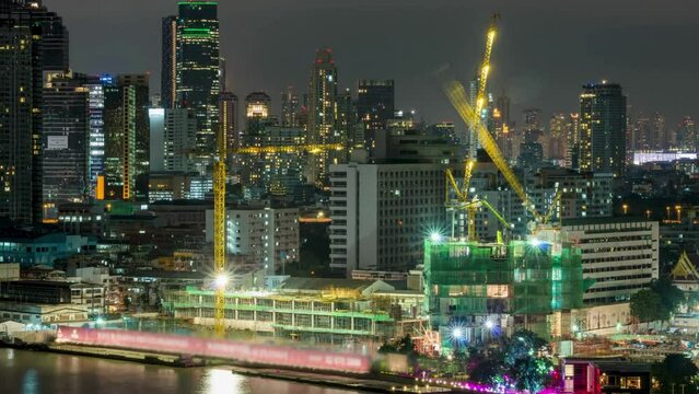 Time lapse of Under construction, Cranes built the building of bangkok cityscape river side on day to night, Thailand, 4k