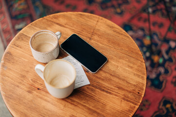 On the table in the cafe there are empty mugs and a bill for payment for breakfast.
