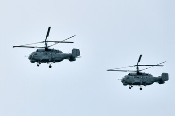 Two Russian military helicopters armed with missiles flies in blue sky, airborne mission of...
