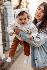 Fototapeta premium A young happy dark-haired woman lifts her daughter up while walking.A family concept.Happy motherhood.