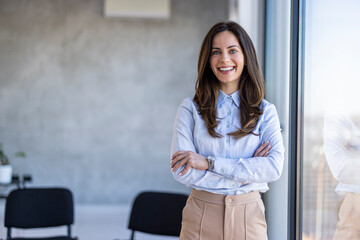 Successful businesswoman standing in creative office and looking at camera. Young woman...
