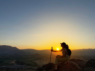 Mujer joven sentada en una roca en la cima deun cerro en una ciudad de Chile, Sudamérica. - obrazy, fototapety, plakaty