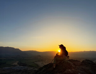 Mujer joven sentada en una roca en la cima deun cerro en una ciudad de Chile, Sudamérica.