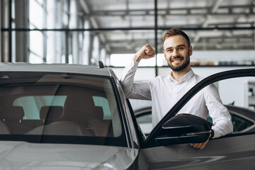 Man in car showroom standing by car and holding car keys