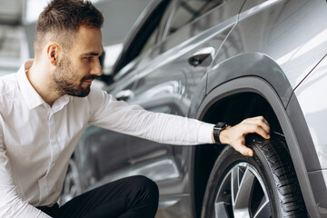 Man checking tires in new car in car showroom © Petro