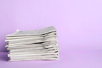 Stack of newspapers on light violet background, space for text. Journalist's work