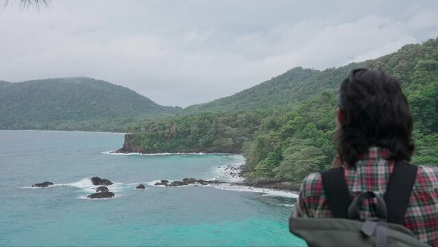 A man photographs a rocky beach on a tropical island