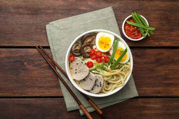 Delicious ramen with meat in bowl served on wooden table, flat lay. Noodle soup