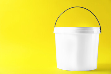 One plastic bucket with lid on yellow background. Space for text