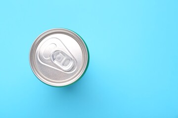 Energy drink in can on light blue background, top view. Space for text