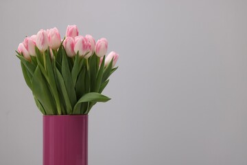 Beautiful bouquet of fresh pink tulips on light grey background. Space for text