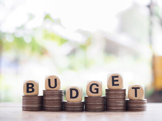 Wooden blocks with the word BUDGET on stack of coins. The concept about budget planning and allocation