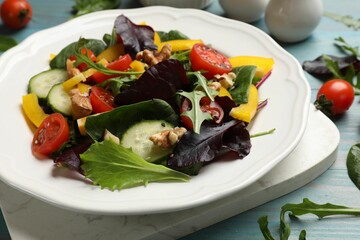 Tasty fresh vegetarian salad on light blue wooden table, closeup