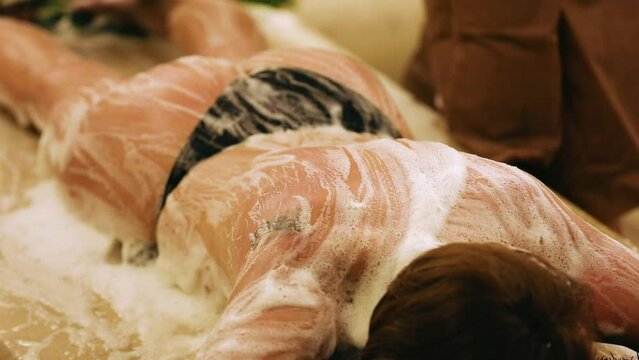 A male bathhouse attendant does a foam procedure to a woman in a hammam