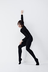 Obraz premium Full-length image of passionate, artistic young woman with smoky eyes makeup, black clothes standing in dynamic pose against white studio background. Concept of fashion, beauty, emotions