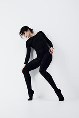 Obraz premium Full-length image of passionate, artistic young woman with smoky eyes makeup, black clothes standing in dynamic pose against white studio background. Concept of fashion, beauty, emotions
