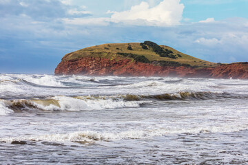 The colourful sandstone cliffs and choppy seas of Havre Aubert, Magdalen Islands, Quebec Province, Canada. - 750676942