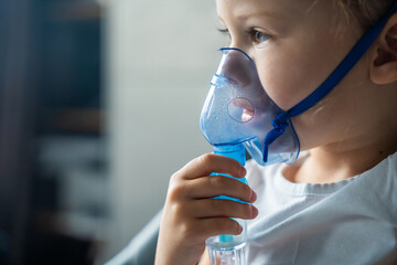 Close up view of little girl are sitting and holding a nebulizer mask leaning against the face, airway treatment concept