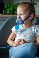 Cute little girl are sitting and holding a nebulizer mask leaning against the face, airway...