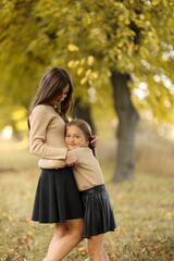 Family day. Young mom and little daughter having fun and enjoy relaxing outdoors in autumn park....