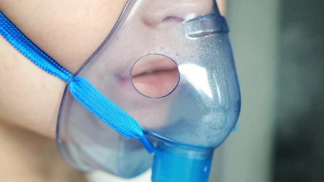 Close up view of little girl are sitting and holding a nebulizer mask leaning against the face, airway treatment concept