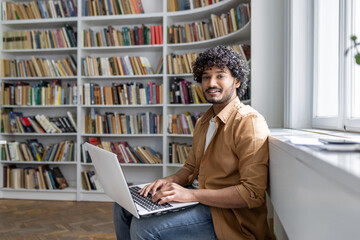 An engaged young adult sits comfortably in a well-lit space, surrounded by books, focused on work...