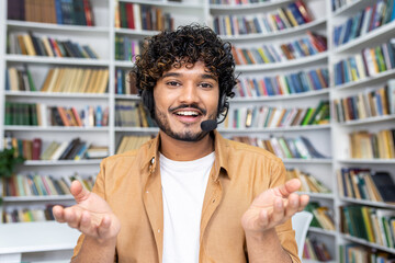 A young man in casual attire stands with an open gesture in a library setting, symbolizing concepts...