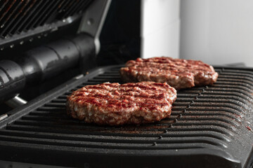 Beef cutlets for hamburger on grill. Preparing burgers at home