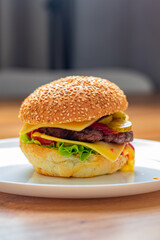 Homemade burger. Hamburger with beef cutlet, cucumber, lettuce, sauce and cheese.