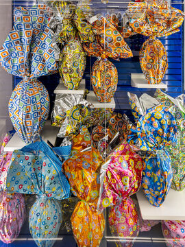 Easter chocolate eggs of various sizes wrapped in mutlicolored and glittery papers displayed for sale in the bakery's display case