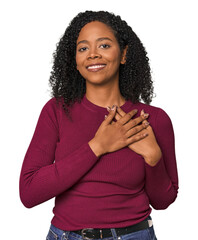Fototapeta na wymiar African American woman in studio setting has friendly expression, pressing palm to chest. Love concept.
