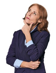Mid-aged Caucasian businesswoman in blazer looking sideways with doubtful and skeptical expression.