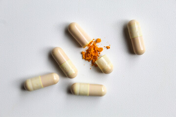 Opened capsule with yellow turmeric powder filling inside. Isolated on white background, flat lay or top view