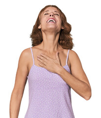 Redhead mid-aged Caucasian woman in studio laughs out loudly keeping hand on chest.