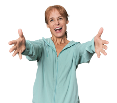 Young mid-aged woman in sportswear in studio feels confident giving a hug to the camera.
