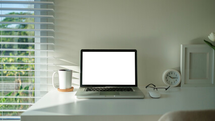 Comfortable workplace with laptop, coffee cup, headphone and glasses. Blank screen for advertising.