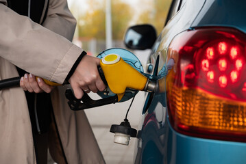 Pumping gas at the gas pump. The woman refuels the car. A woman at a gas station. A woman refuels a car with gasoline at a gas station. Fuel injection  - obrazy, fototapety, plakaty