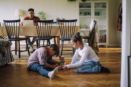 Siblings playing Jenga while sitting on floor at home