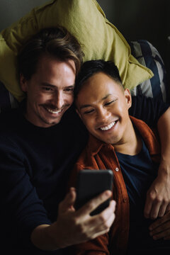 High angle view of smiling gay couple using smart phone at home