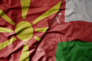 big waving national colorful flag of oman and national flag of macedonia .