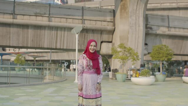 A beautiful Muslim woman happily poses for a photo with a skytrain while traveling in the heart of Bangkok. .She smiles confidently as the camera captures her in the bustling city. civilization city.