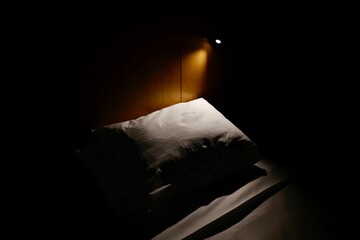 暗い寝室のベッドサイトランプに照らされた枕