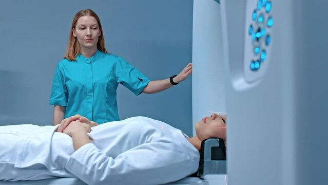 Neurologist doctor observing process of MRI examination. Nurse sending patient to computer tomography capsule on moving table. Magnetic resonance imaging of brain. Laboratory with medical equipment