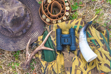 Various hunting equipment: hunting hat, belt with cartridges, glasses, horn and camouflage clothes...