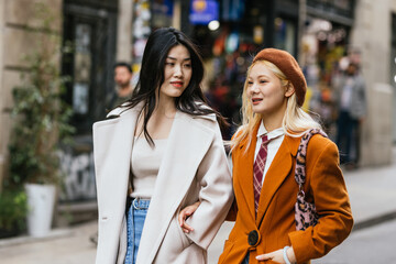 Obraz premium Two stylish young women walking on the street together.