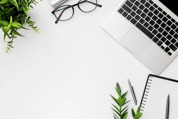A office desk with a laptop, notebook, and a single plant